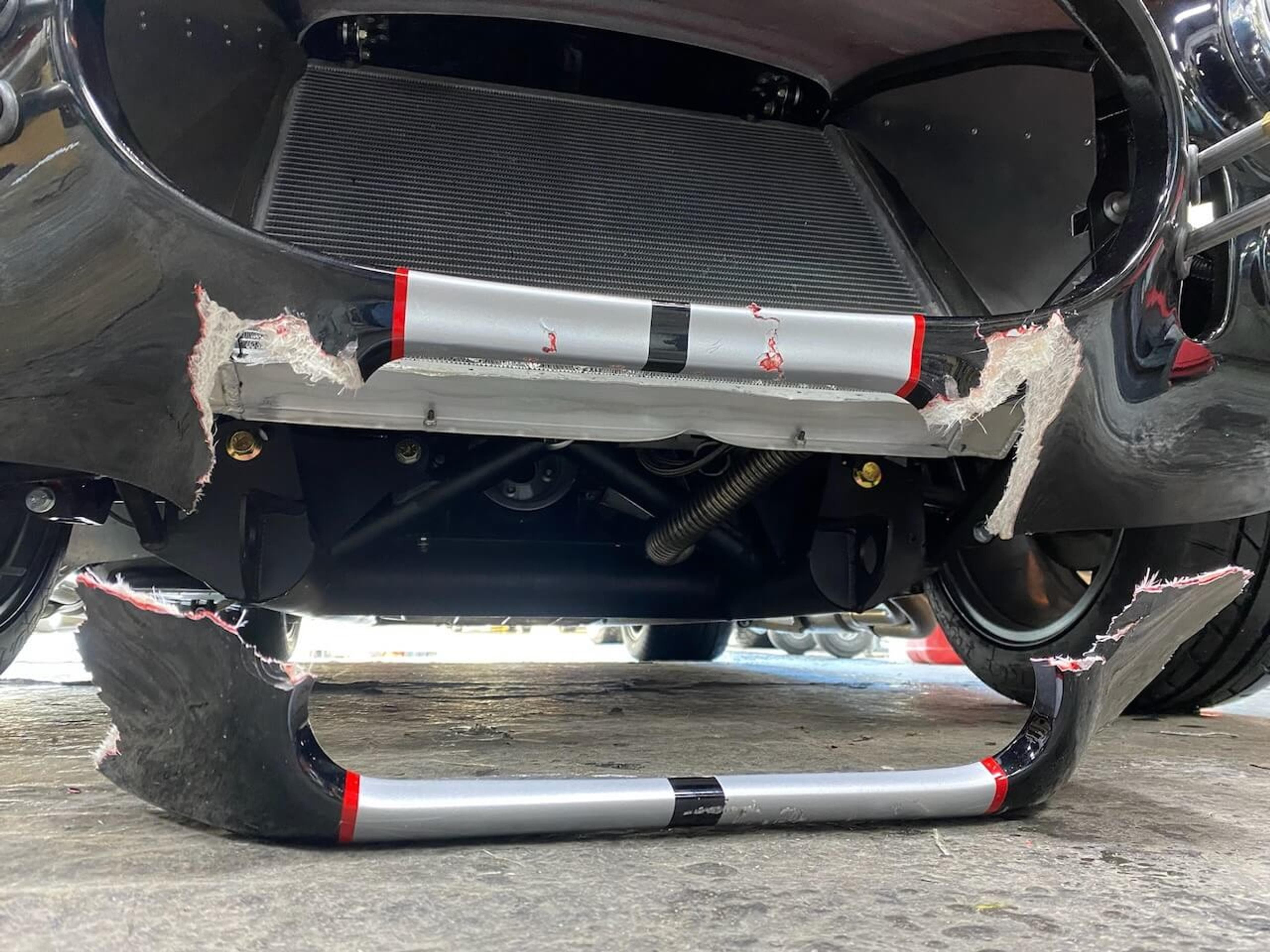 Severe fiberglass damage before repair Front lower body section of a Shelby Cobra-style roadster with broken and torn fiberglass