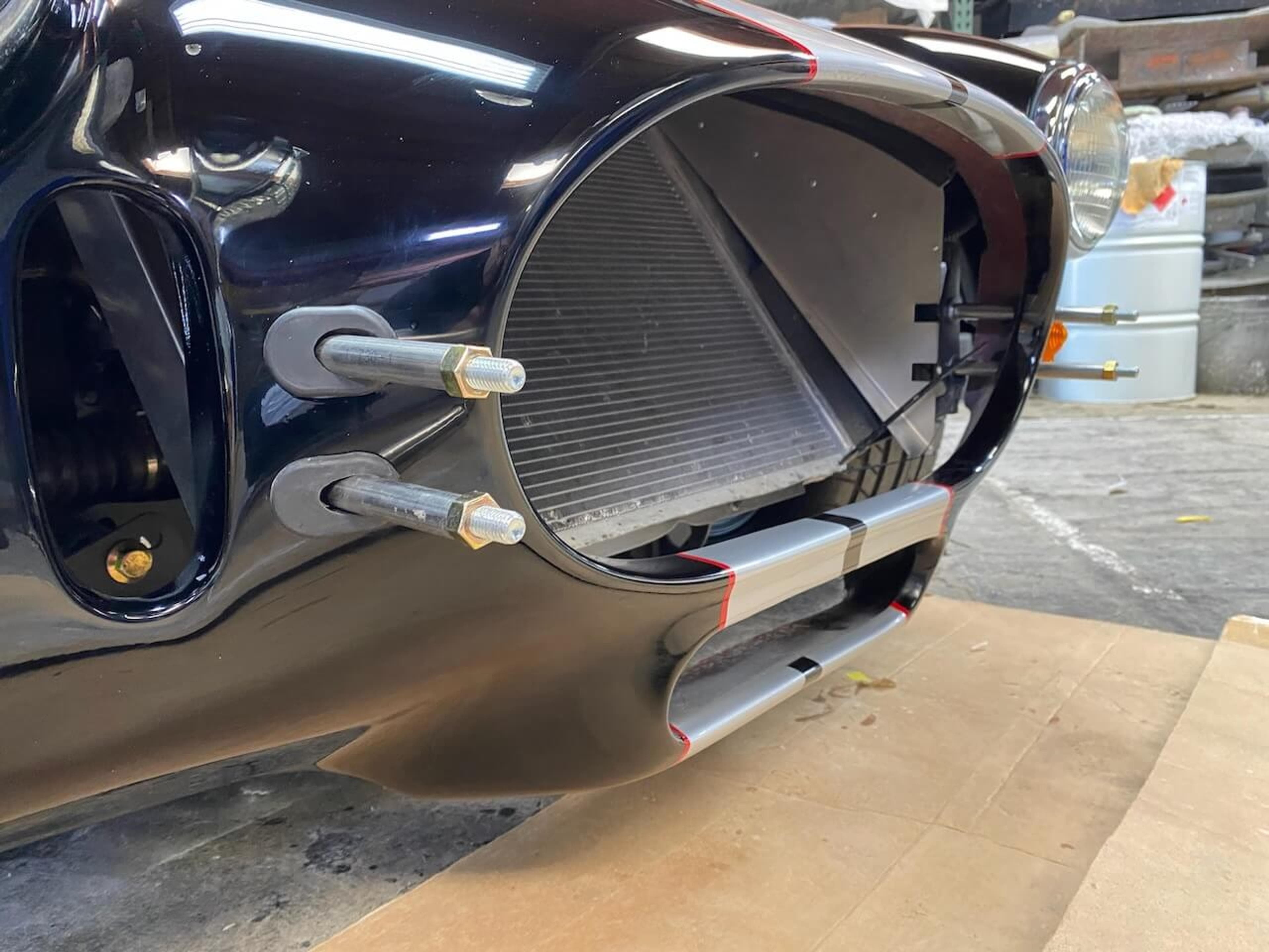 Repaired front section after refinishing Close-up of the restored lower front opening on a Shelby Cobra-style roadster after fiberglass repair