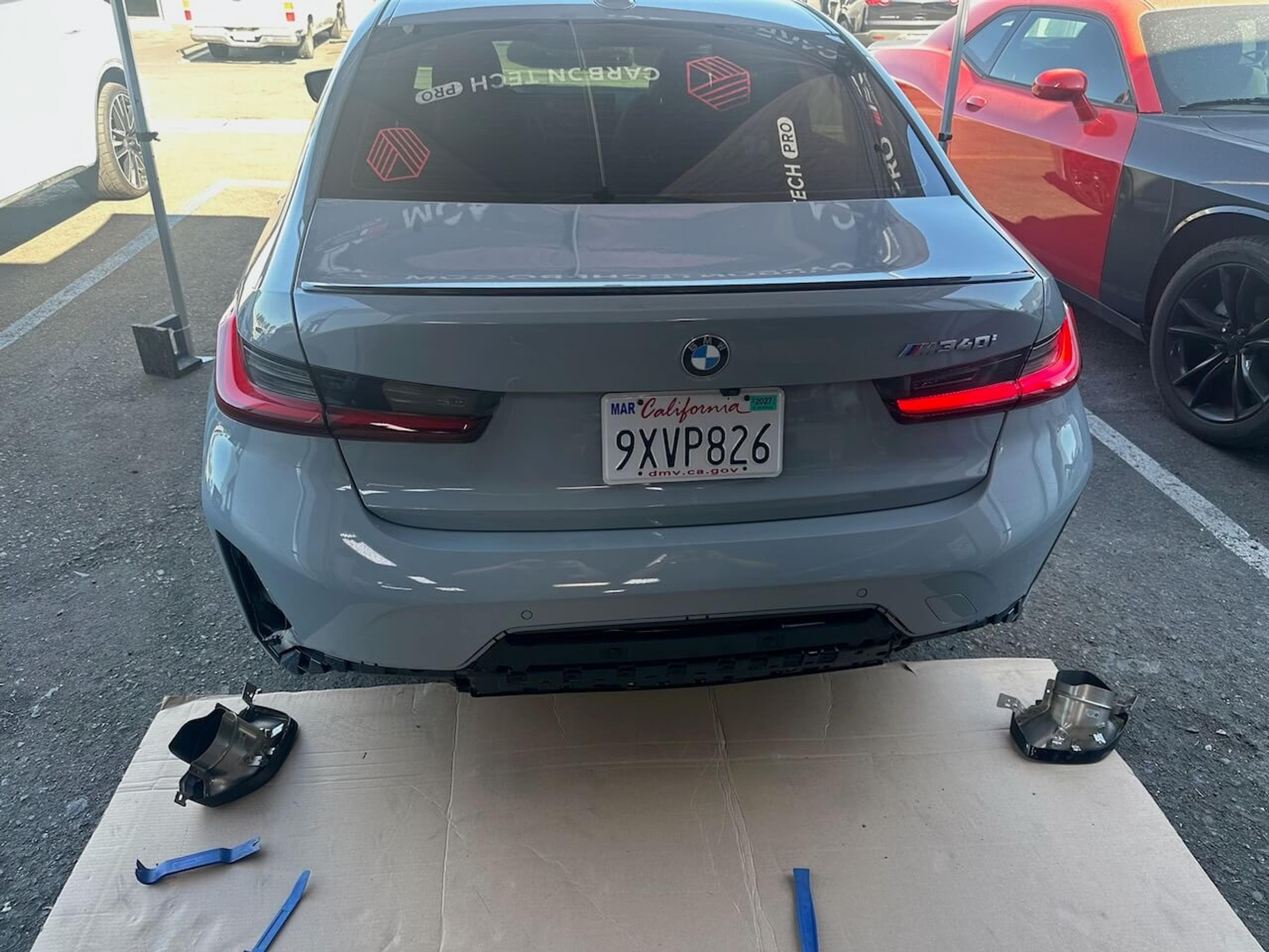 Rear diffuser and bumper detail Close-up of the installed carbon fiber rear diffuser on a gray BMW M340i