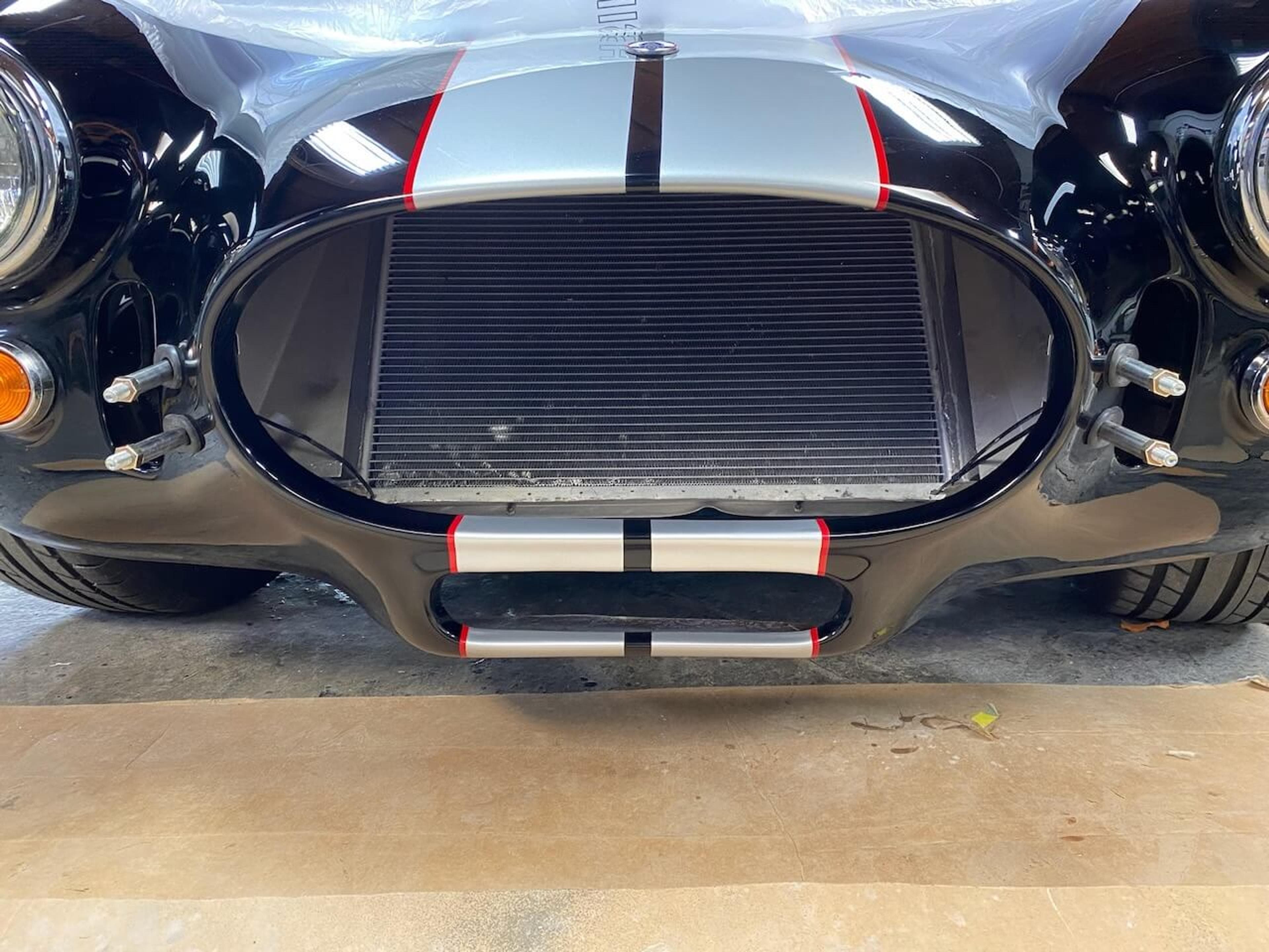 Completed front-end fiberglass repair Front view showing the repaired and refinished lower valance on a Shelby Cobra-style roadster