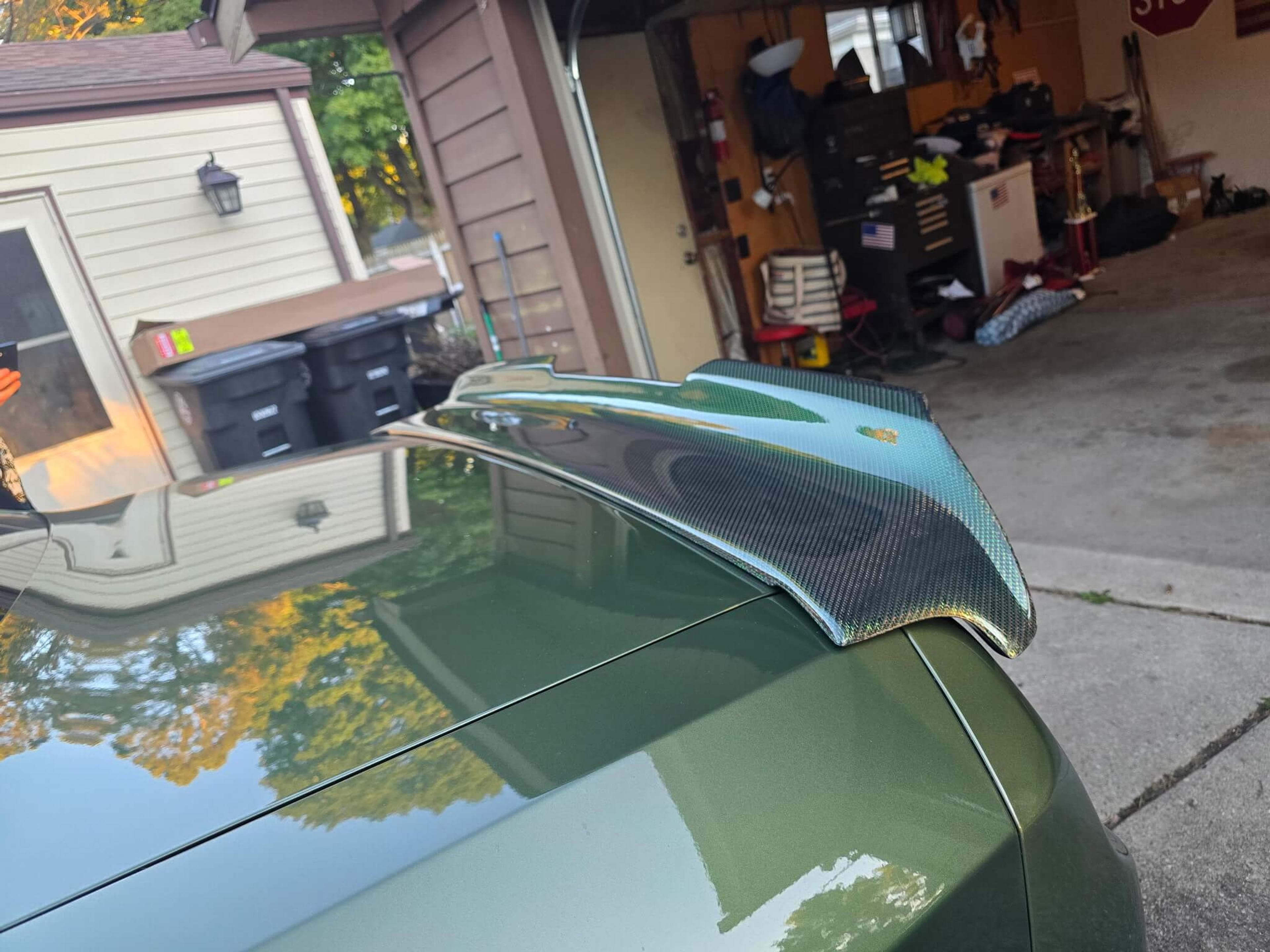 Installed green reflective carbon fiber spoiler Close-up of a green reflective carbon fiber spoiler fitted to a Dodge Challenger trunk.
