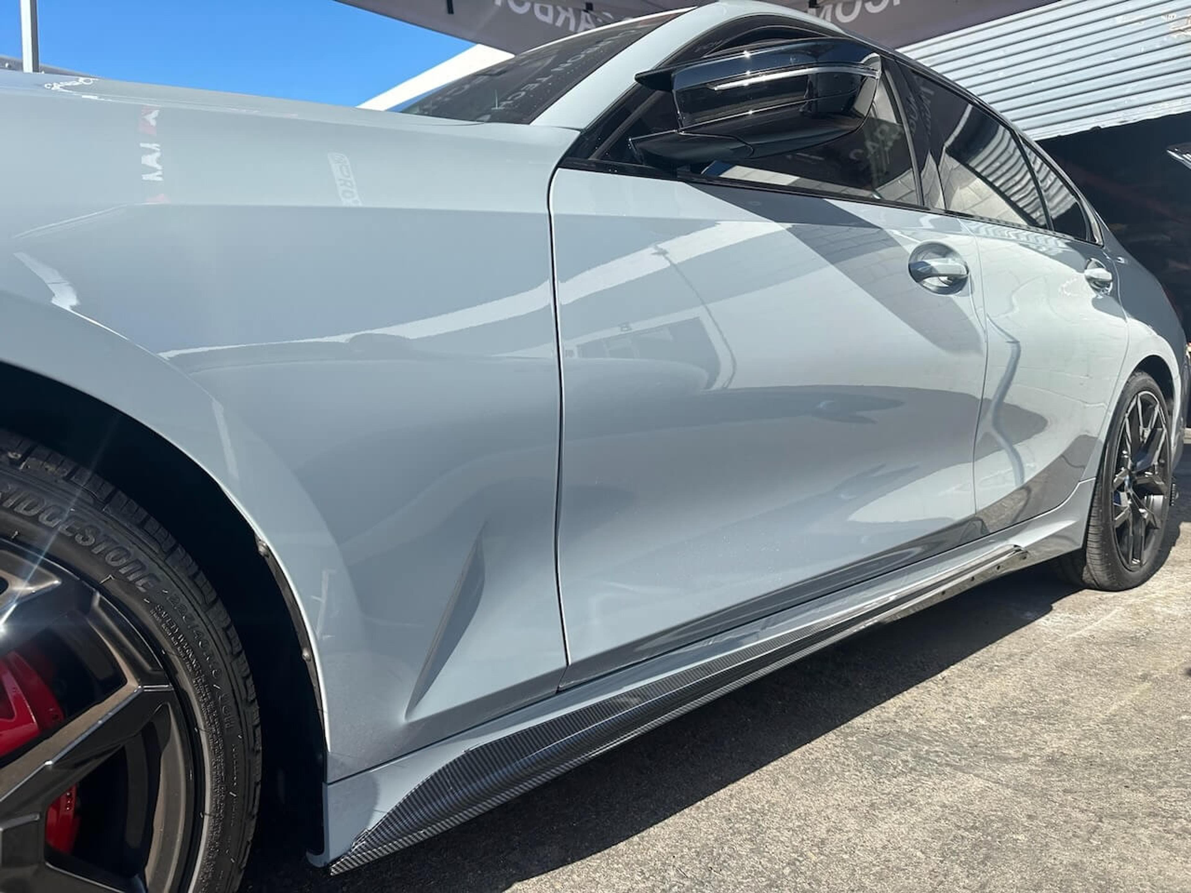 Carbon fiber side skirts installed Side view of a 2026 BMW M340i showing the installed carbon fiber side skirts