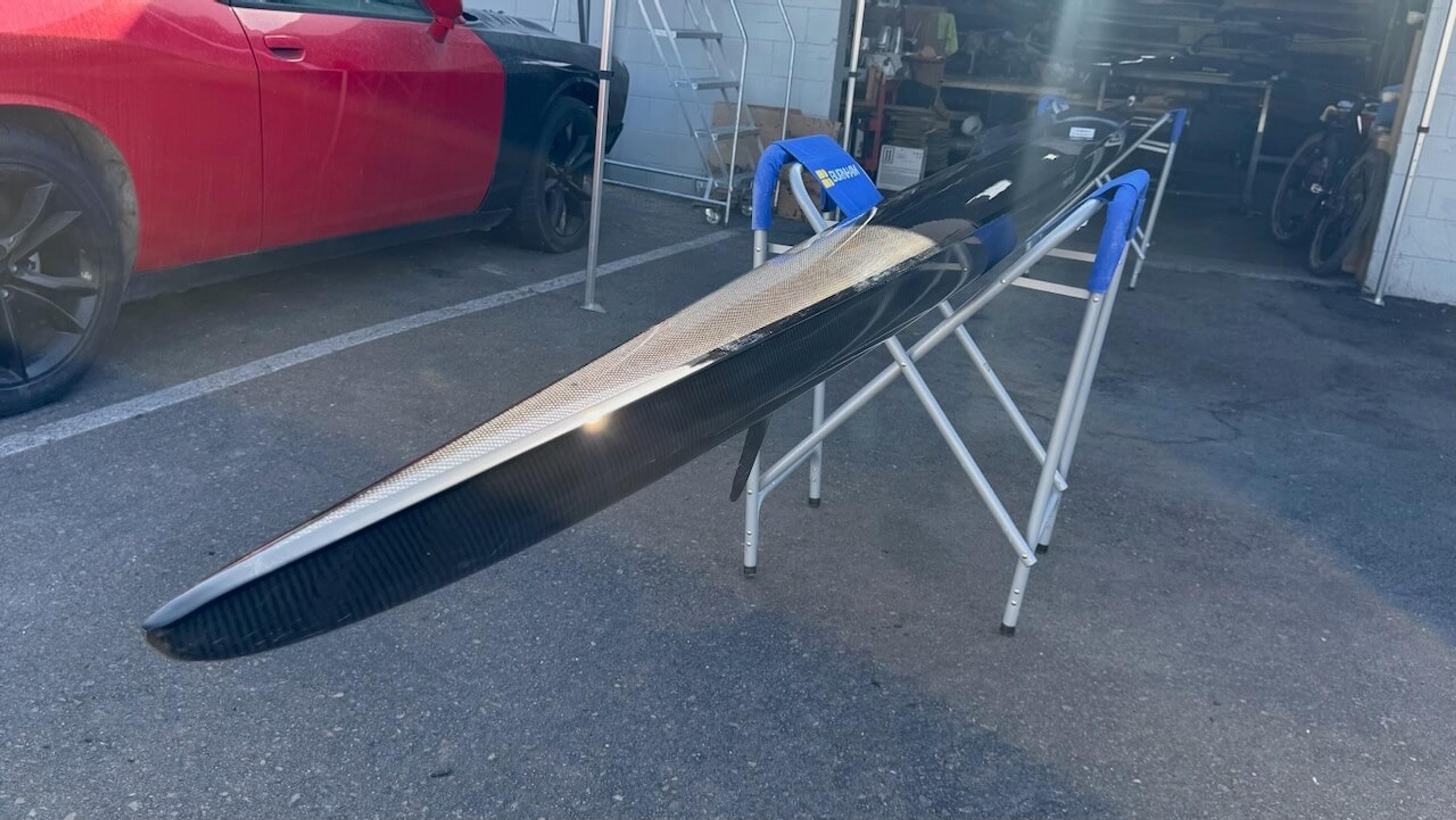 Carbon fiber repair in progress Fluidesign rowing shell supported on stands during carbon fiber repair and refinishing
