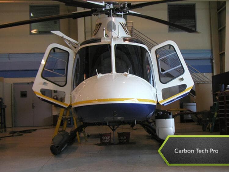 Front view of a white, blue, and yellow NYPD helicopter inside a hangar with its side doors open.